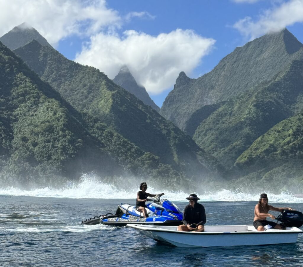 Tahiti tourists riding boats and jet skis in the ocean overlooking the mountains
