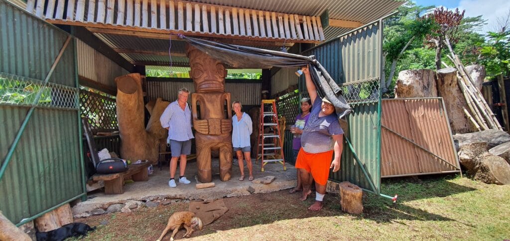 Tourists posing with natives in front of a statue